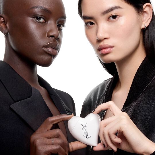 Two models in black clothing holding Care Crush, the first on-the-go skincare accessory by YSL Beauty.