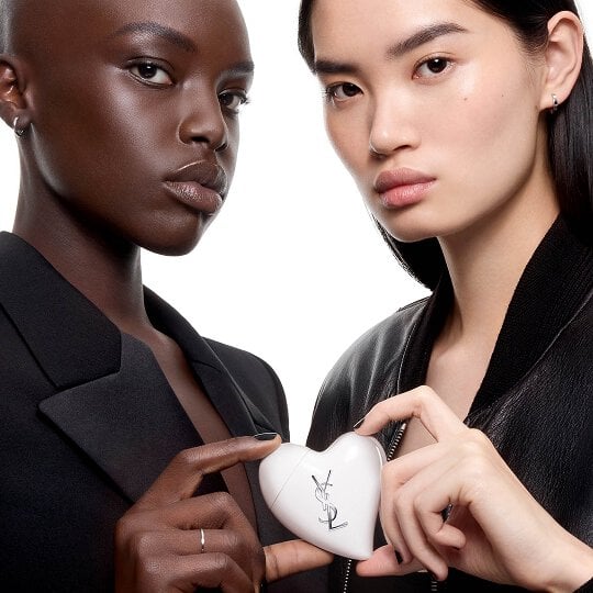 Two models in black clothing holding Care Crush, the first on-the-go skincare accessory by YSL Beauty.