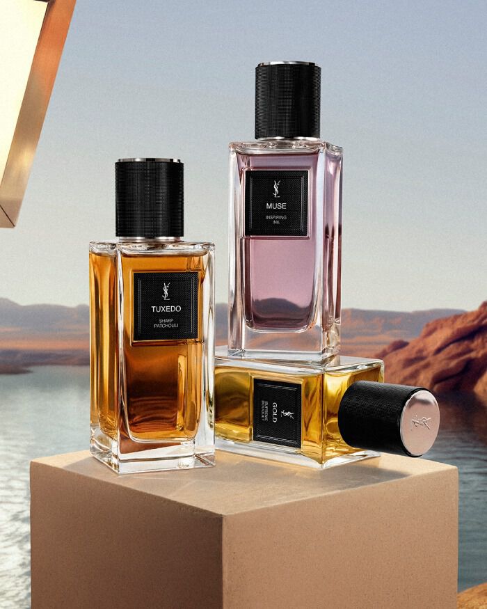 Le Vestiaire Des Parfums fragrances: MUSE, TUXEDO, and GOLD bottle, on a pedestal in a desert landscape.