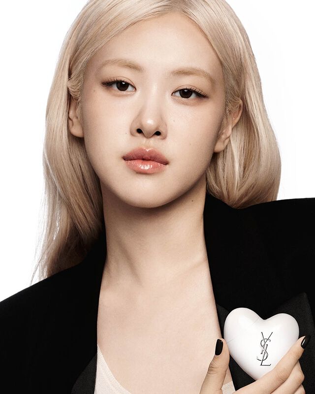 Rose from Blackpink in a black blazer holding Care Crush, a white heart-shaped YSL skincare product.